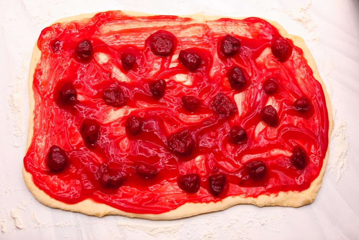 Strawberry cinnamon rolls are going to become a tradition in your house after you make these! The secret is the freeze-dried strawberries mixed with the lemon zest in the glaze - the flavor is to die for! Strawberry pie filling spread out over the rolled out dough.