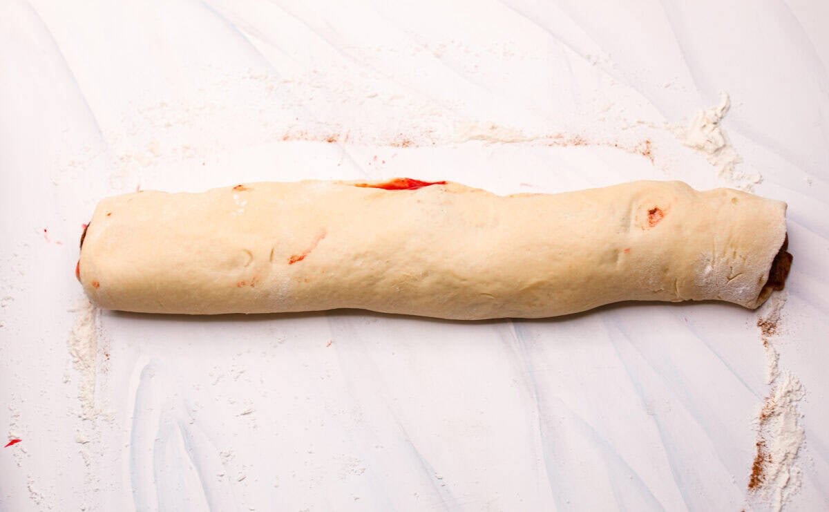 Strawberry cinnamon rolls are going to become a tradition in your house after you make these! The secret is the freeze-dried strawberries mixed with the lemon zest in the glaze - the flavor is to die for! Dough and filling rolled up into a log.