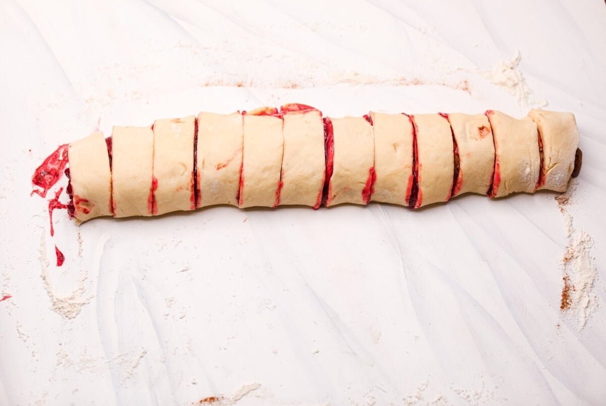 Strawberry cinnamon rolls are going to become a tradition in your house after you make these! The secret is the freeze-dried strawberries mixed with the lemon zest in the glaze - the flavor is to die for! Dough log rolled up and cut into sliced, unbaked strawberry cinnamon rolls.