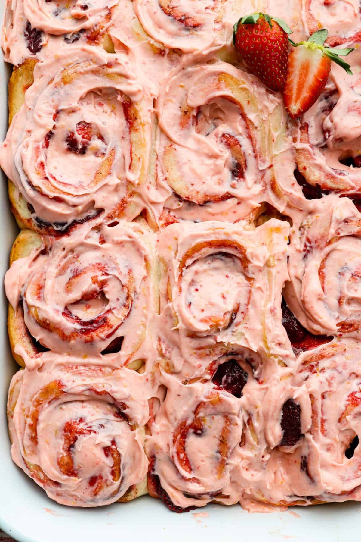 Once you try these strawberry cinnamon rolls, they’ll be a family staple! The secret? Freeze-dried strawberries and lemon zest in the glaze! They are seriously so good! Overhead shot of strawberry cinnamon rolls frosted with lemon cream cheese glaze.