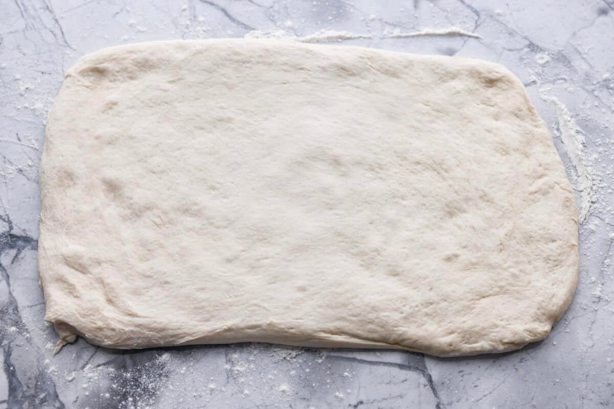 Pizza Hut breadsticks are warm, fluffy, and buttery, but this copycat recipe is even better! Coated in seasoning, parmesan, and melted butter, they’re next-level delicious. Breadstick dough rolled out onto a floured surface.