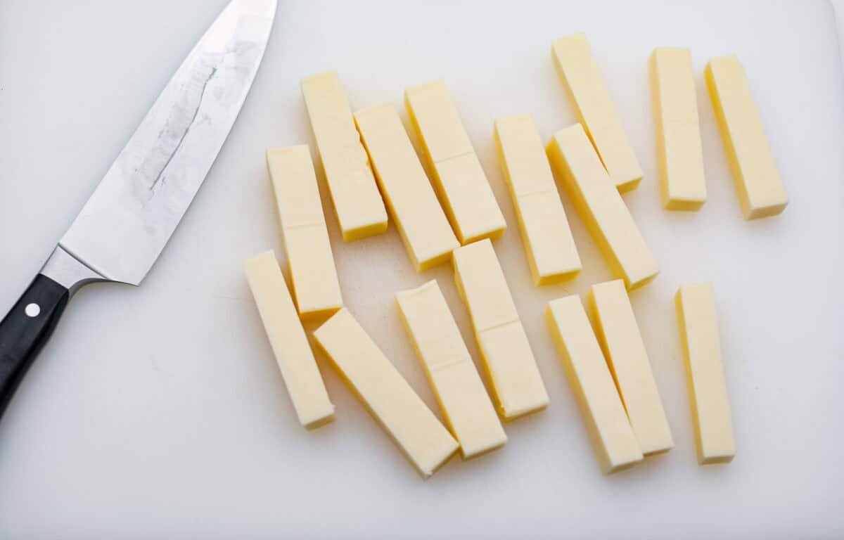 The secret to perfect mozzarella sticks comes down to three key steps: using the right mozzarella, double breading for a sturdy crust, and fully freezing them before frying. I’ve broken down these expert tips below! Process shots of mozzarella cheese cut up into sticks.