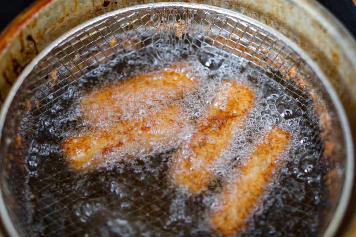 The secret to perfect mozzarella sticks comes down to three key steps: using the right mozzarella, double breading for a sturdy crust, and fully freezing them before frying. I’ve broken down these expert tips below! Overhead shot of the double breaded mozzarella sticks frying in oil.
