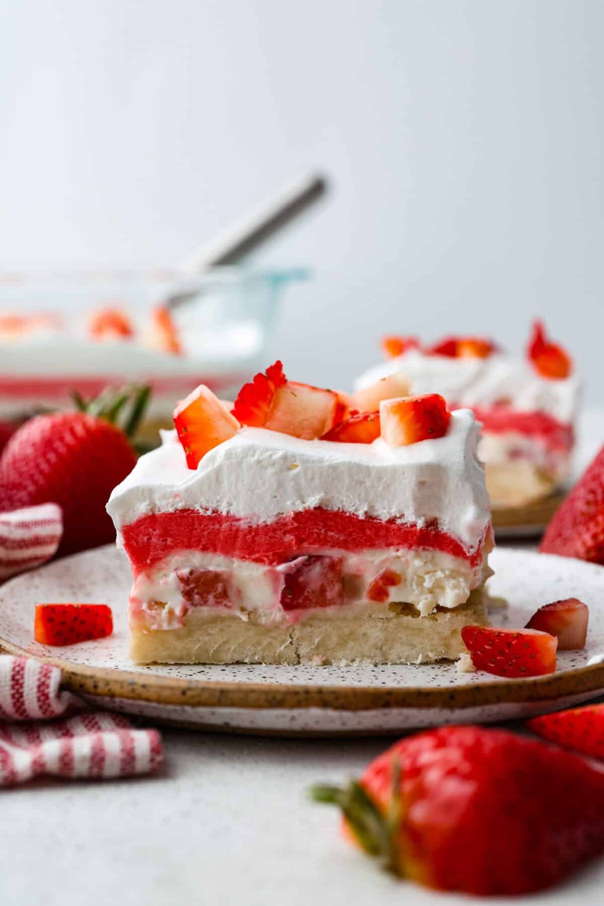 My Strawberry Delight is the ultimate summer showstopper! Buttery crust, juicy strawberries, sweet jello, and fluffy topping—one bite and everyone’s hooked. Side shot of strawberry delight on a plate.