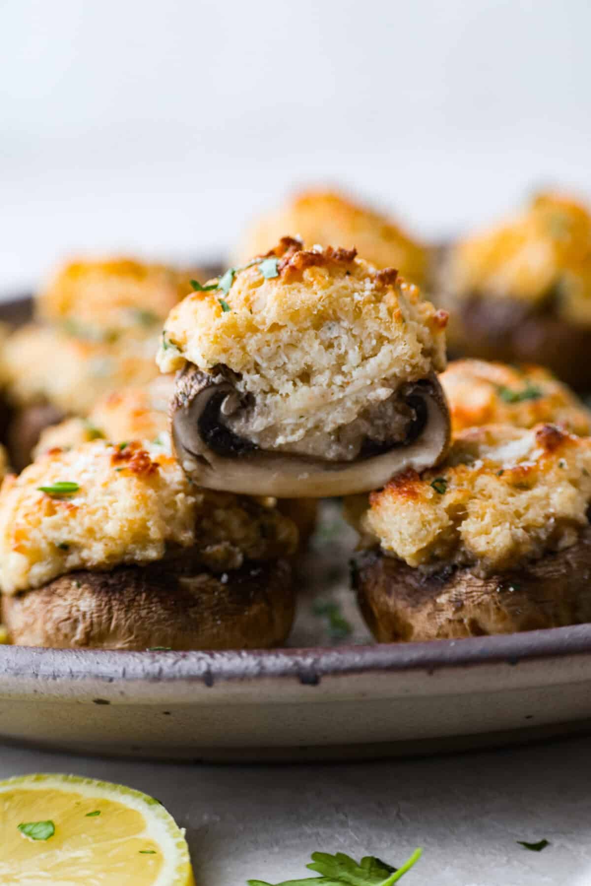 These Crab Stuffed Mushrooms are a deliciously savory appetizer, perfect for impressing guests at any gathering. With a rich crab filling in every bite, they’re sure to be a crowd favorite! Side shot of a crab stuffed mushroom cut in half.