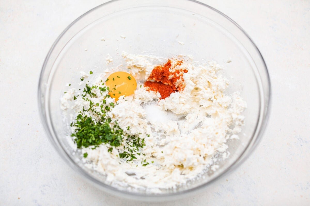 These Crab Stuffed Mushrooms are a deliciously savory appetizer, perfect for impressing guests at any gathering. With a rich crab filling in every bite, they’re sure to be a crowd favorite! Overhead shot of the whisked cream cheese with egg yolk, paprika and salt in a mixing bowl.