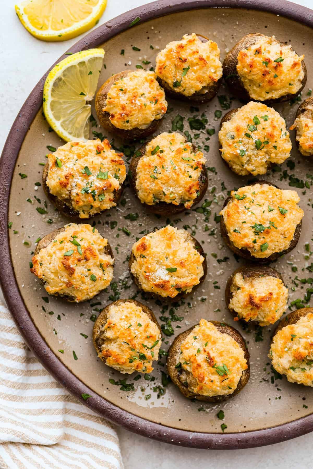 These Crab Stuffed Mushrooms are a deliciously savory appetizer, perfect for impressing guests at any gathering. With a rich crab filling in every bite, they’re sure to be a crowd favorite! Overhead shot of baked crab stuffed mushrooms on a serving plate.
