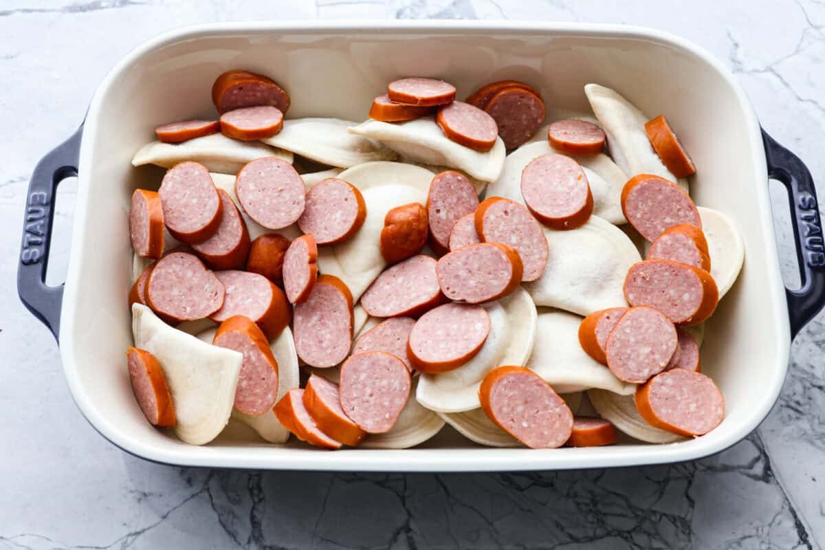 This isn’t your average Pierogi Casserole. While most stick to one type of cheese, I use a blend for ooey-gooey cheesy creaminess and cozy flavor in every bite. Pierogis and kielbasa sausage in the baking dish.