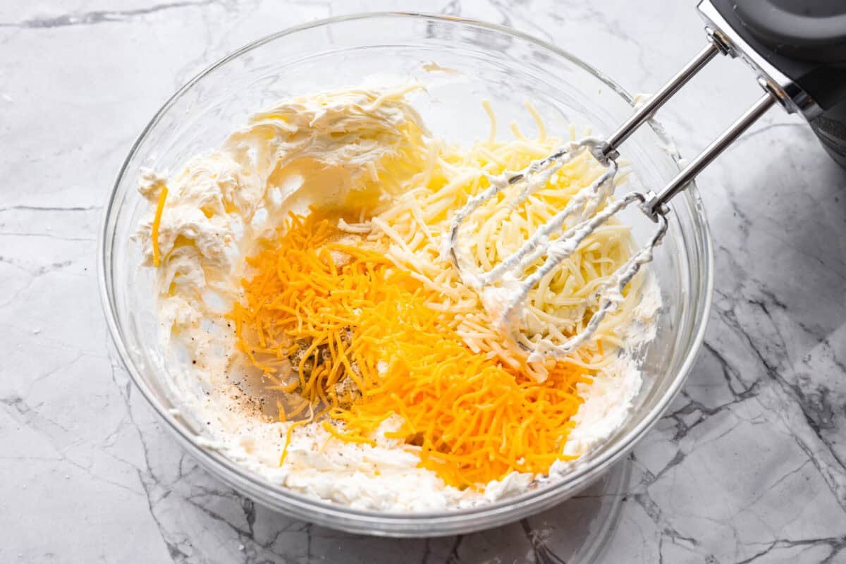 This isn’t your average Pierogi Casserole. While most stick to one type of cheese, I use a blend for ooey-gooey cheesy creaminess and cozy flavor in every bite. Someone using a hand mixer to make the creamy cheese mixture.