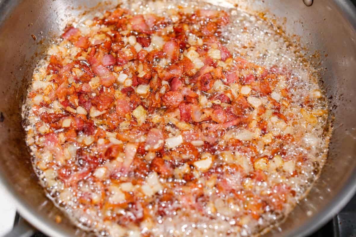 Kickstart your day with this hearty Amish Breakfast Casserole! It's loaded with crispy bacon, tender hash browns, and gooey melted cheese. This dish is a crowd-pleaser that’s perfect for family breakfasts and holiday mornings! Overhead shot of the garlic cooking with the bacon and onions.