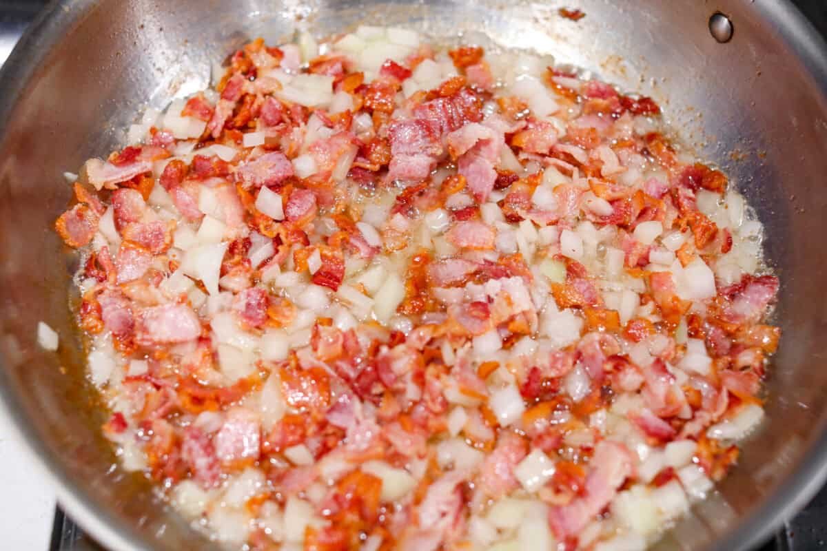 Kickstart your day with this hearty Amish Breakfast Casserole! It's loaded with crispy bacon, tender hash browns, and gooey melted cheese. This dish is a crowd-pleaser that’s perfect for family breakfasts and holiday mornings! Overhead shot of bacon and onions cooking together in a skillet.
