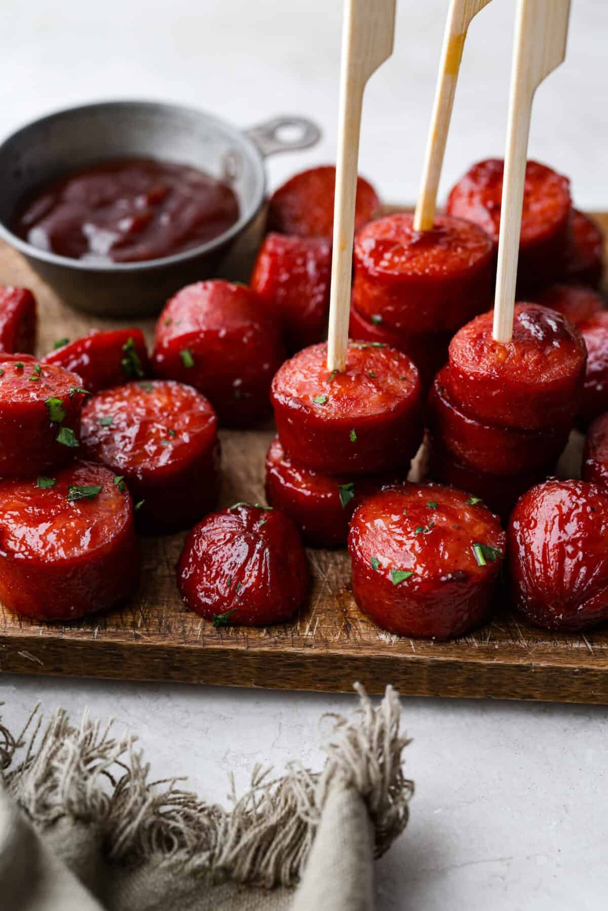 Kielbasa Bites are the ultimate crowd-pleasing appetizer! With their smoky, savory flavor and caramelized glaze sweetness, these bite-sized snacks are easy to make and always a hit at parties, game days, or anytime you need a quick appetizer! Angle shot of kielbasa bites stacked on a serving dish.
