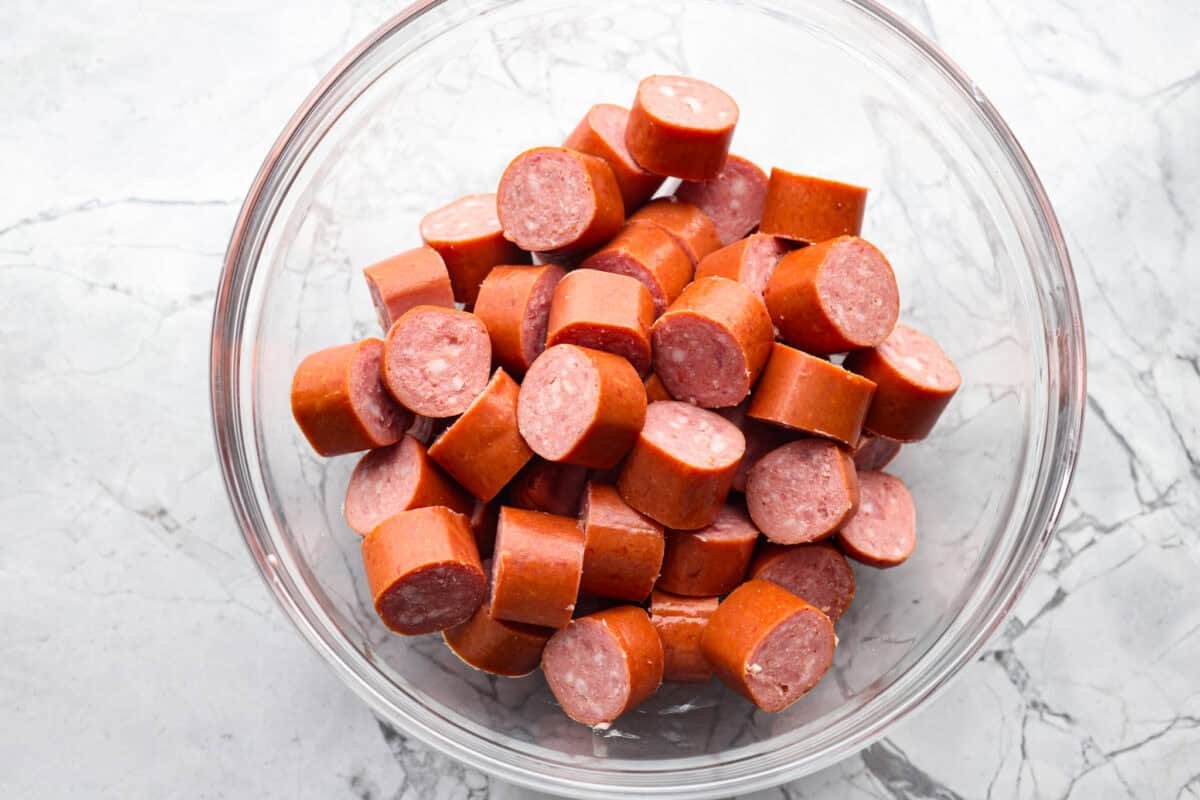 Kielbasa Bites are the ultimate crowd-pleasing appetizer! With their smoky, savory flavor and caramelized glaze sweetness, these bite-sized snacks are easy to make and always a hit at parties, game days, or anytime you need a quick appetizer! Overhead shot of sliced kielbasa in a bowl.