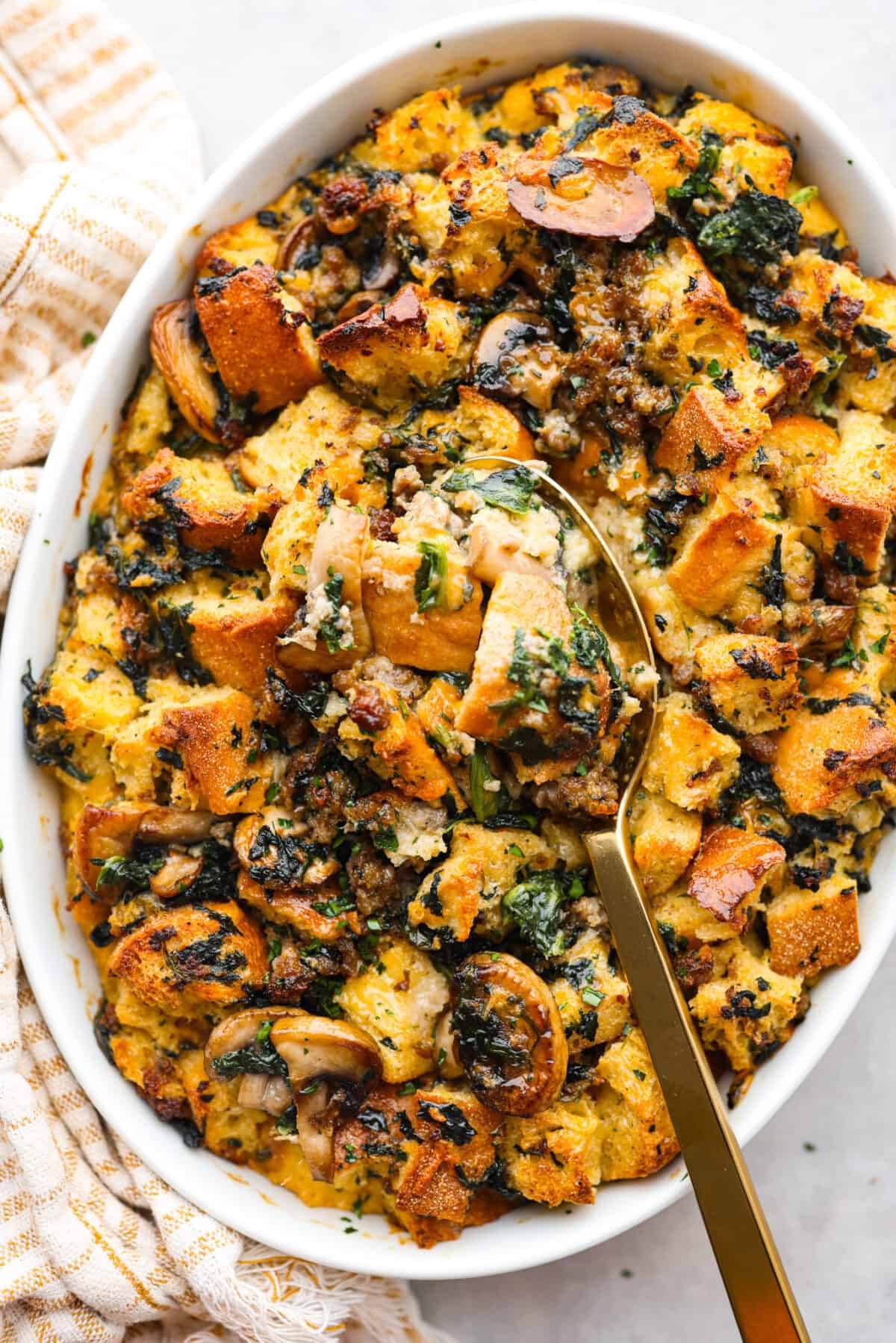 This breakfast strata is bursting with savory sausage, tender mushrooms, soft bread pieces, and melty cheddar. Perfect for your next holiday or family breakfast. It is packed with so much delicious flavor and texture that it will leave you wanting seconds! Overhead shot of breakfast strata.