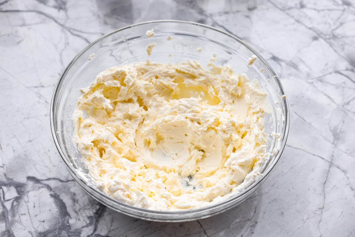 This everything bagel cheese ball combines the creamy richness of cheese with the savory blend of everything bagel seasoning! It's an irresistible appetizer you can serve with crackers, bagel chips, or veggies! Everyone will love it! Overhead shot of cream cheese mixed in a bowl.