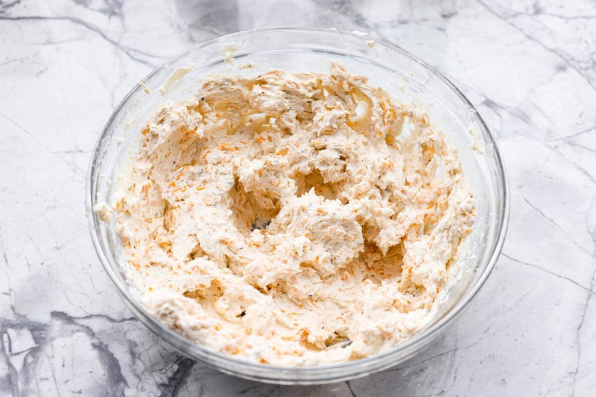 This everything bagel cheese ball combines the creamy richness of cheese with the savory blend of everything bagel seasoning! It's an irresistible appetizer you can serve with crackers, bagel chips, or veggies! Everyone will love it! Overhead shot of cheese ball ingredients mixed in a bowl.