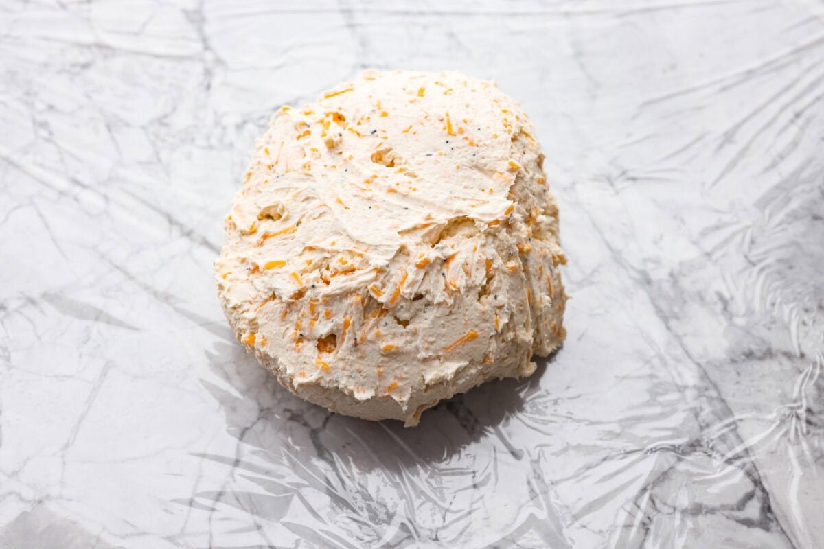 This everything bagel cheese ball combines the creamy richness of cheese with the savory blend of everything bagel seasoning! It's an irresistible appetizer you can serve with crackers, bagel chips, or veggies! Everyone will love it! Overhead shot of the cheeseball formed into a ball.