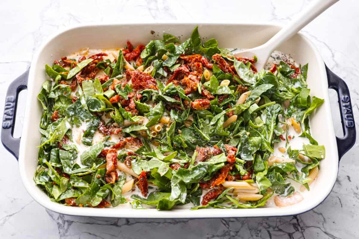 You all love my Crockpot Tuscan Chicken, and I know casseroles are a favorite as well. So, I combined them into this irresistibly delicious Tuscan Chicken Casserole! Someone stirring all of the ingredients in the baking dish.