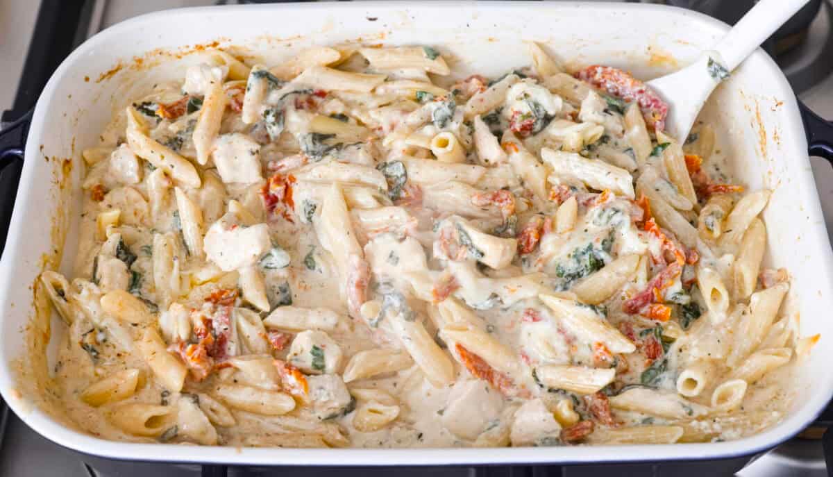 You all love my Crockpot Tuscan Chicken, and I know casseroles are a favorite as well. So, I combined them into this irresistibly delicious Tuscan Chicken Casserole! Someone stirring the melty cheese into the casserole.