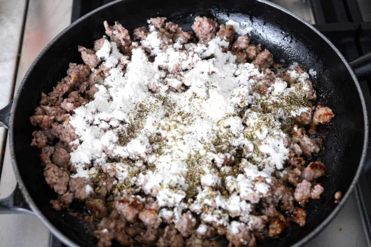Homemade sausage gravy is perfect for a comforting breakfast! In just 15 minutes and with a few simple ingredients, you’ll have a delicious, hearty gravy to top fluffy biscuits. Overhead shot of cooked sausage with flour and seasonings added to it.