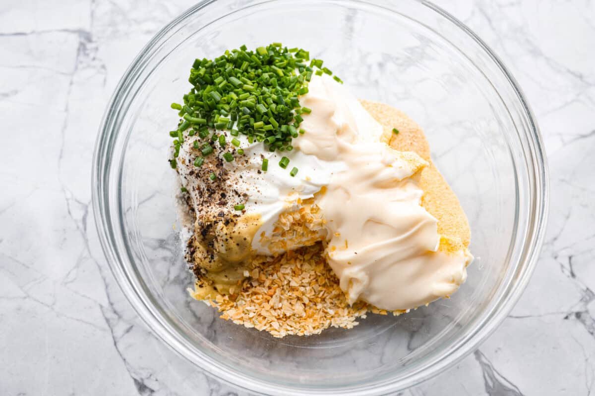 This sour cream and onion dip has become a staple at all of our family get togethers. It's the perfect appetizer, even the kids cant get enough! The rich and creamy dip is packed with incredible onion flavor. Overhead shot of all of the ingredients in a bowl.