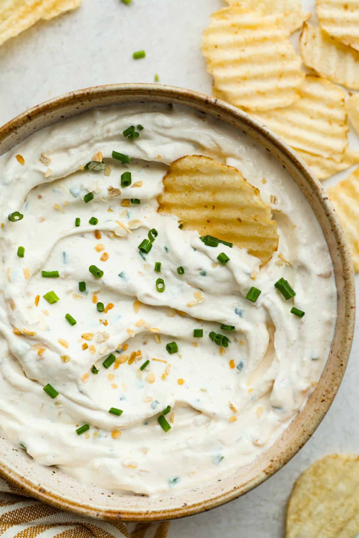 This sour cream and onion dip has become a staple at all of our family get togethers. It's the perfect appetizer, even the kids cant get enough! The rich and creamy dip is packed with incredible onion flavor. Overhead shot of sour cream and onion dip with a chip sticking out of it.