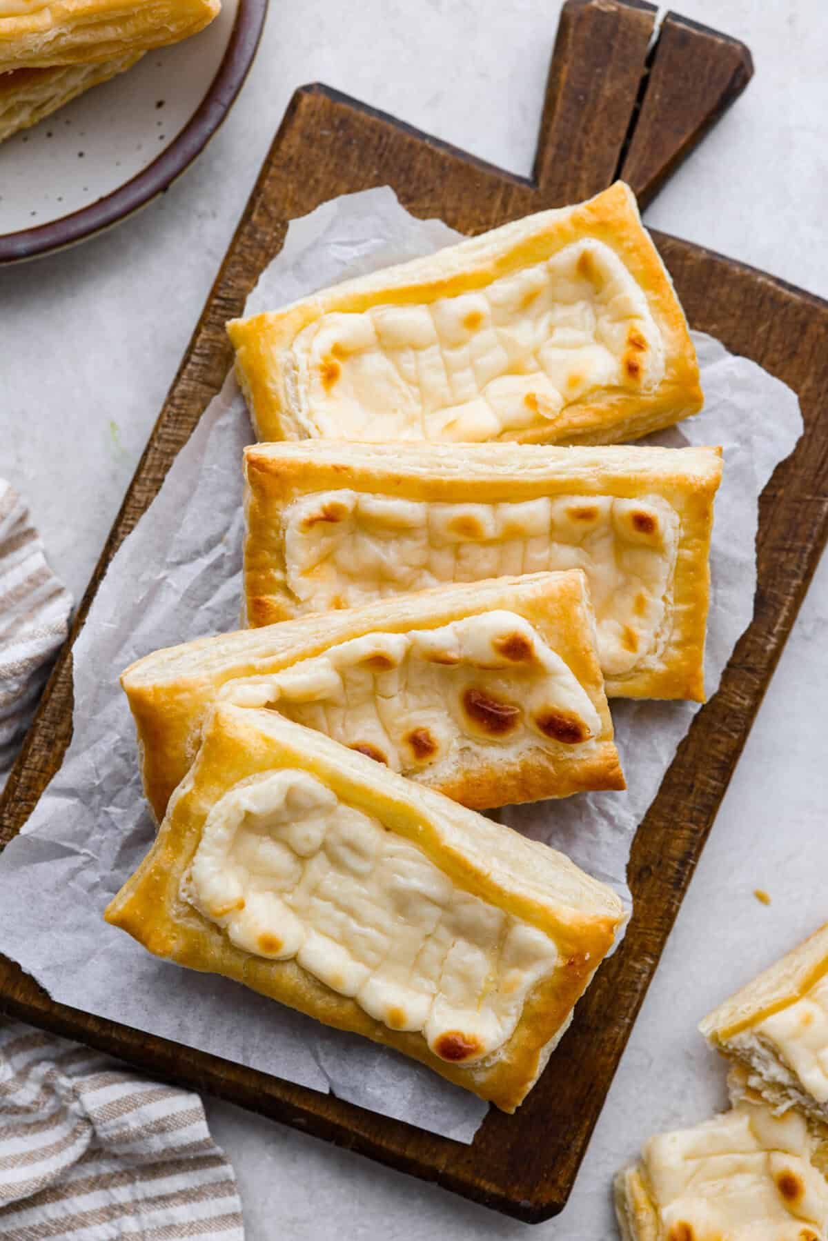 Craving the buttery goodness of a Starbucks cream cheese Danish? Now you can make it right at home! This easy copycat recipe uses flaky puff pastry and a sweet, creamy cheese filling for a treat that’s just as delicious, maybe even better! Overhead shot of Starbucks cream cheese danishes on a cutting board.
