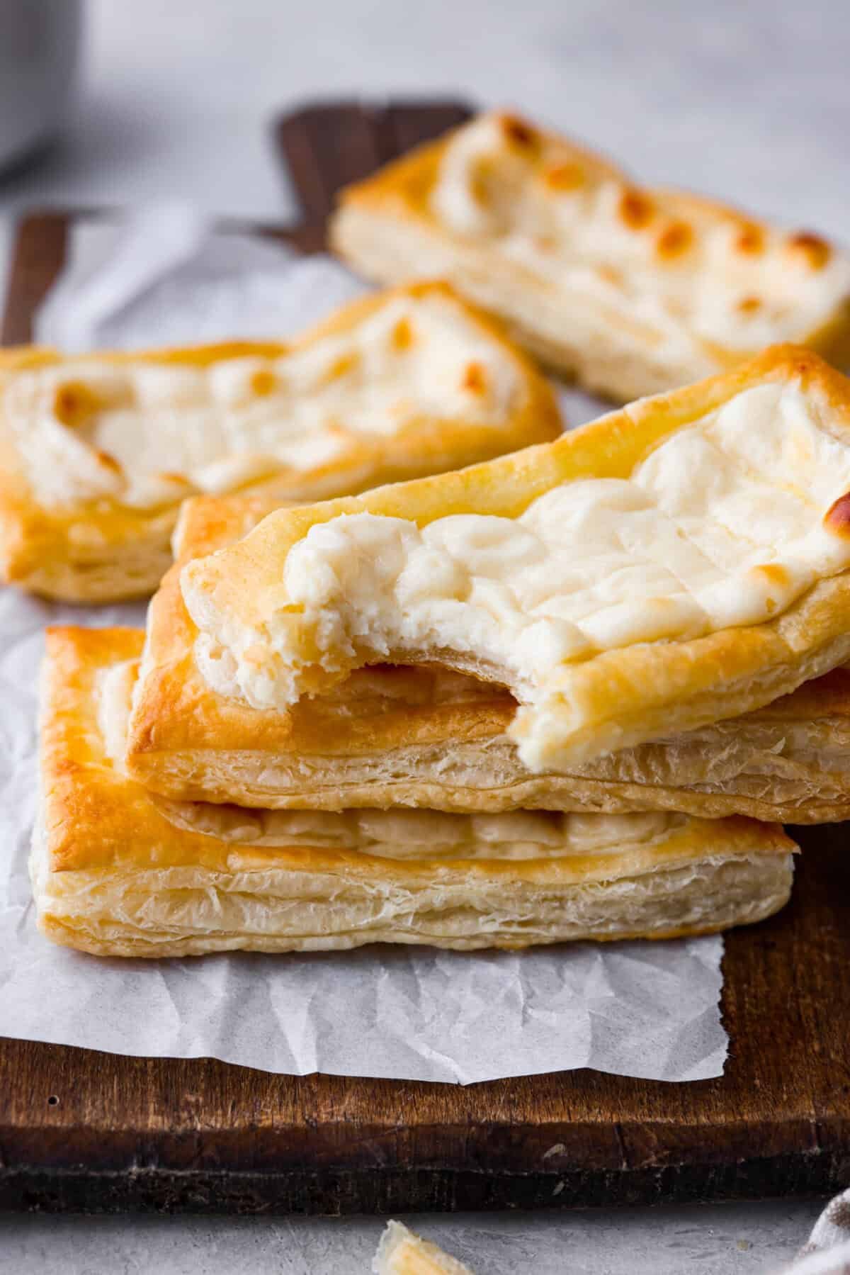 Craving the buttery goodness of a Starbucks cream cheese Danish? Now you can make it right at home! This easy copycat recipe uses flaky puff pastry and a sweet, creamy cheese filling for a treat that’s just as delicious, maybe even better! Angle shot of stacked Starbucks cream cheese danishes. One has a bite taken out.