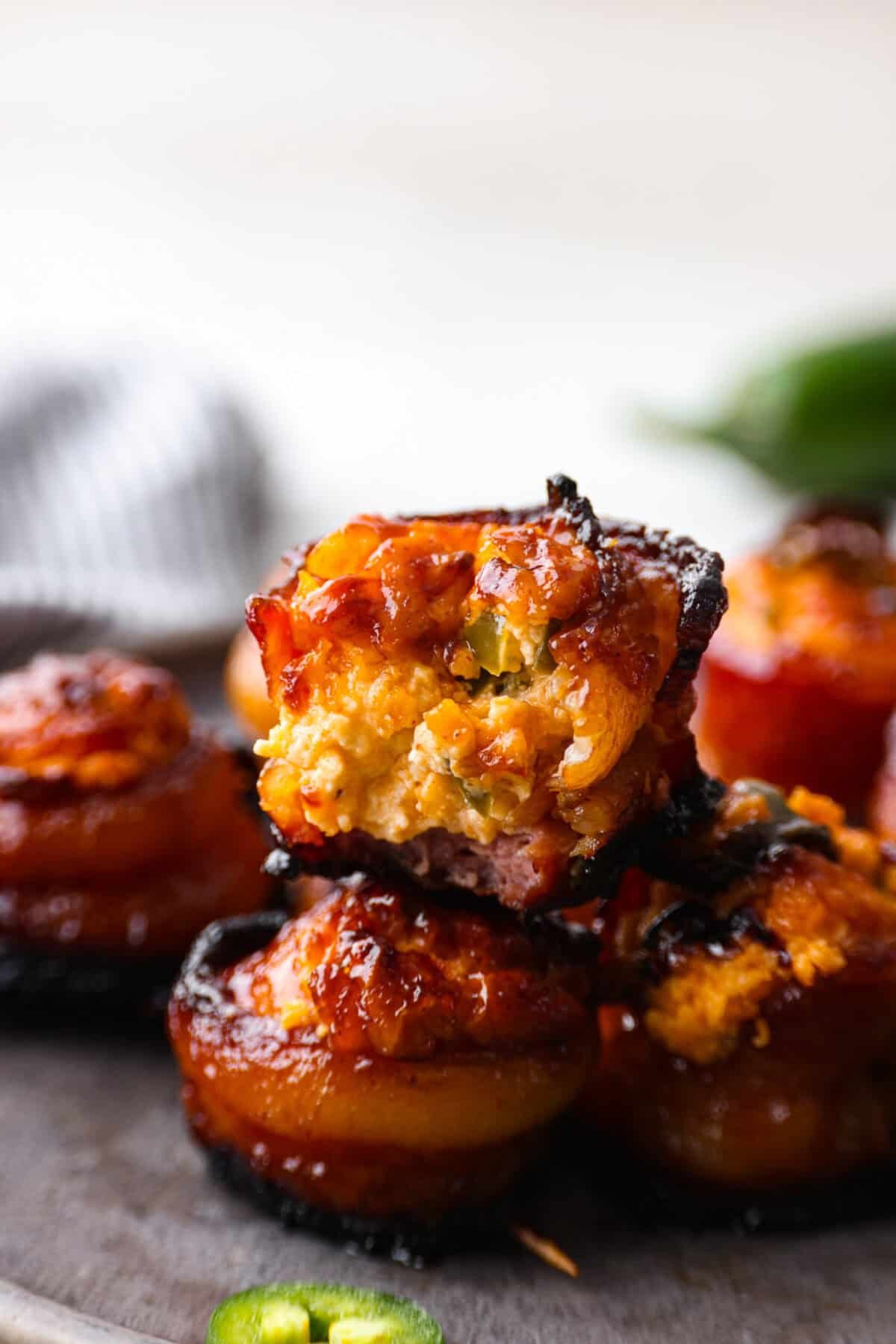 Get ready to wow your taste buds with Pig Shots! These bite-sized creations feature smoky bacon wrapped around savory sausage, filled with a creamy, flavorful cream cheese mixture. Shaped like mini shot glasses, they’re the perfect snack for game day, parties, or anytime you're looking for a unique appetizer. Side shot os stacked pig shots. One of them has a bite taken out of it.
