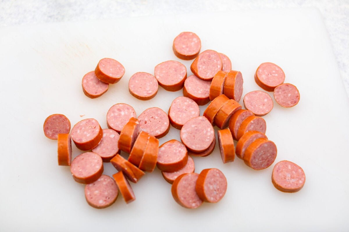 Get ready to wow your taste buds with Pig Shots! These bite-sized creations feature smoky bacon wrapped around savory sausage, filled with a creamy, flavorful cream cheese mixture. Shaped like mini shot glasses, they’re the perfect snack for game day, parties, or anytime you're looking for a unique appetizer. Overhead shot of sliced up sausage.