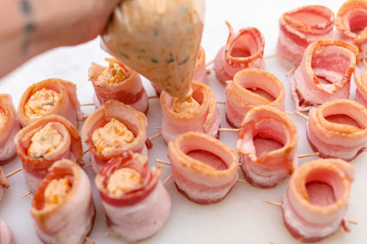 https://www.target.com/p/excalibur-seasoning-smokehouse-bbq-rub-seasoning-6oz-shaker-bottle/-/A-93218011#lnk=sametab Overhead shot of someone adding filling to the top of the bacon wrapped pork slices.
