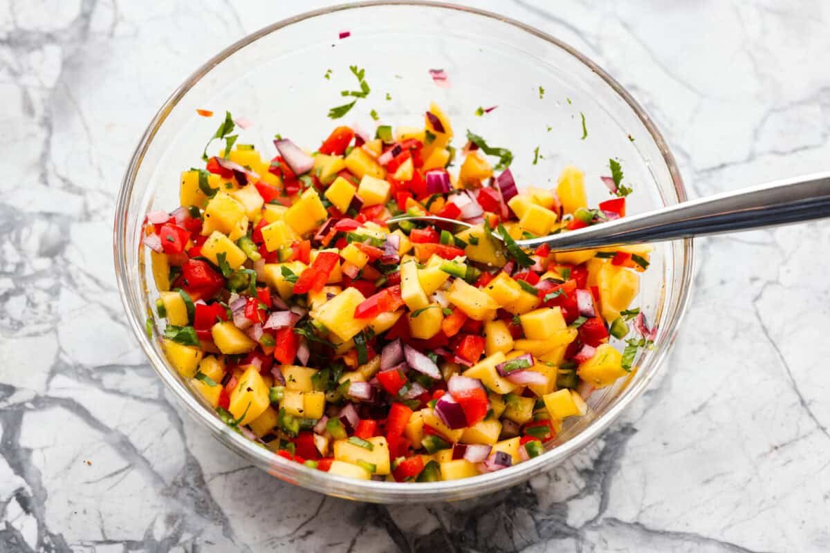 I’m obsessed with salmon, and this Mango Salsa Salmon might just be my new favorite! It’s super flavorful, fast to cook, and somehow my kids don’t fight me on it. That bright, juicy salsa on top? Freaking amazing. I could eat it every night! Bowl of mango salsa ingredients diced and mixed together.