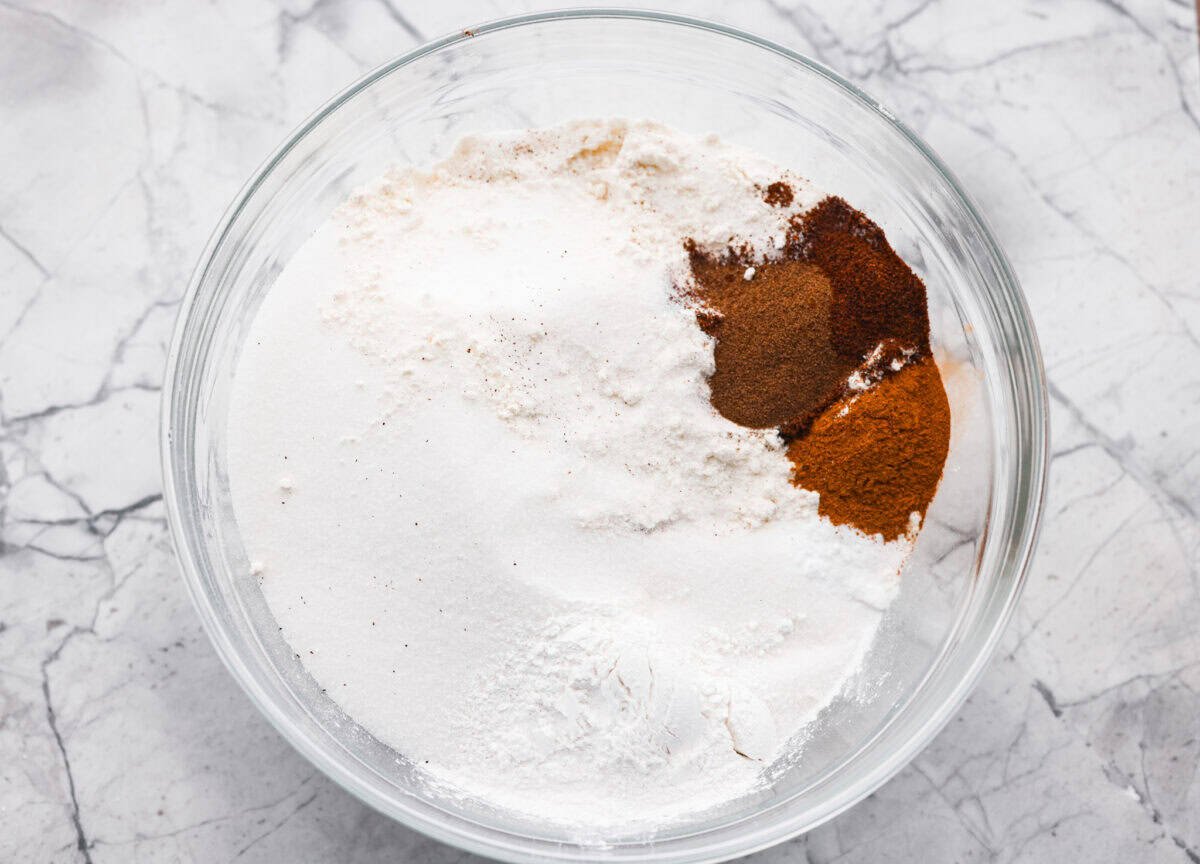 It's time to bring back the retro Tomato Soup Cake! In 1960, it was the first recipe to appear on a soup label. It resembles a moist and delicious spice cake topped with cream cheese frosting. I know you're skeptical, but trust me, it will knock your socks off! Overhead shot of dry ingredients in a bowl.