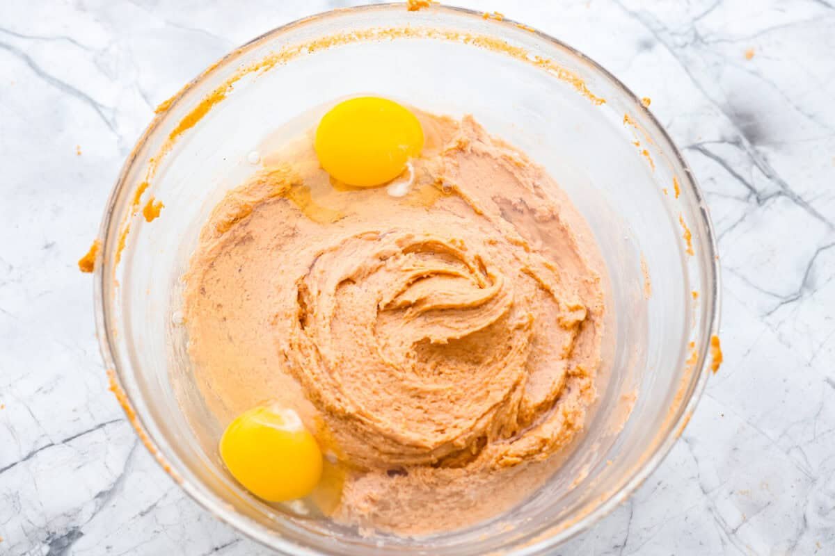 It's time to bring back the retro Tomato Soup Cake! In 1960, it was the first recipe to appear on a soup label. It resembles a moist and delicious spice cake topped with cream cheese frosting. I know you're skeptical, but trust me, it will knock your socks off! Wet and dry ingredients are all mixed together in a bowl with 2 eggs crack on top.