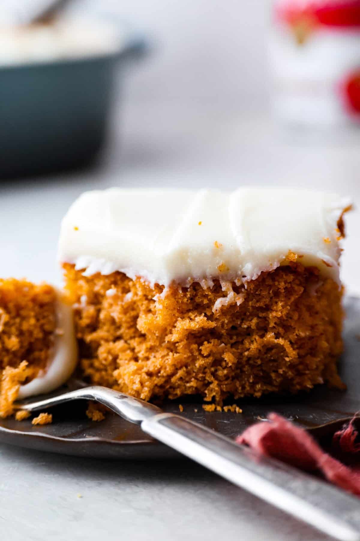 It's time to bring back the retro Tomato Soup Cake! In 1960, it was the first recipe to appear on a soup label. It resembles a moist and delicious spice cake topped with cream cheese frosting. I know you're skeptical, but trust me, it will knock your socks off! Close up shot of a slice of tomato soup cake.
