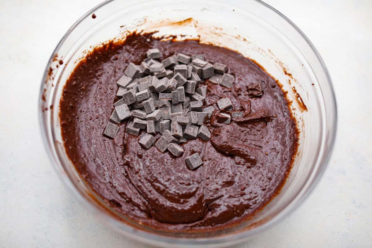 Rich, fudgy, and packed with deep chocolate flavor, Guinness Brownies are a must-try for any dessert lover! The stout beer enhances the cocoa, adding a subtle, malty depth of flavor that makes these brownies rich and irresistibly delicious. Overhead shot of chocolate chunks added to the mixed brownie batter.