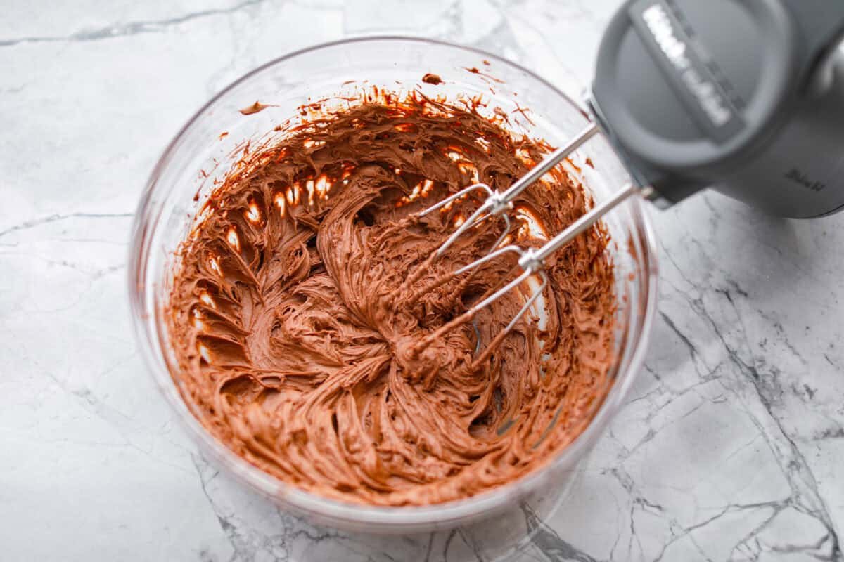 Rich, fudgy, and packed with deep chocolate flavor, Guinness Brownies are a must-try for any dessert lover! The stout beer enhances the cocoa, adding a subtle, malty depth of flavor that makes these brownies rich and irresistibly delicious. Overhead shot of someone using a hand mixer to whip up the chocolate chip mixture to make a fluffy ganache.