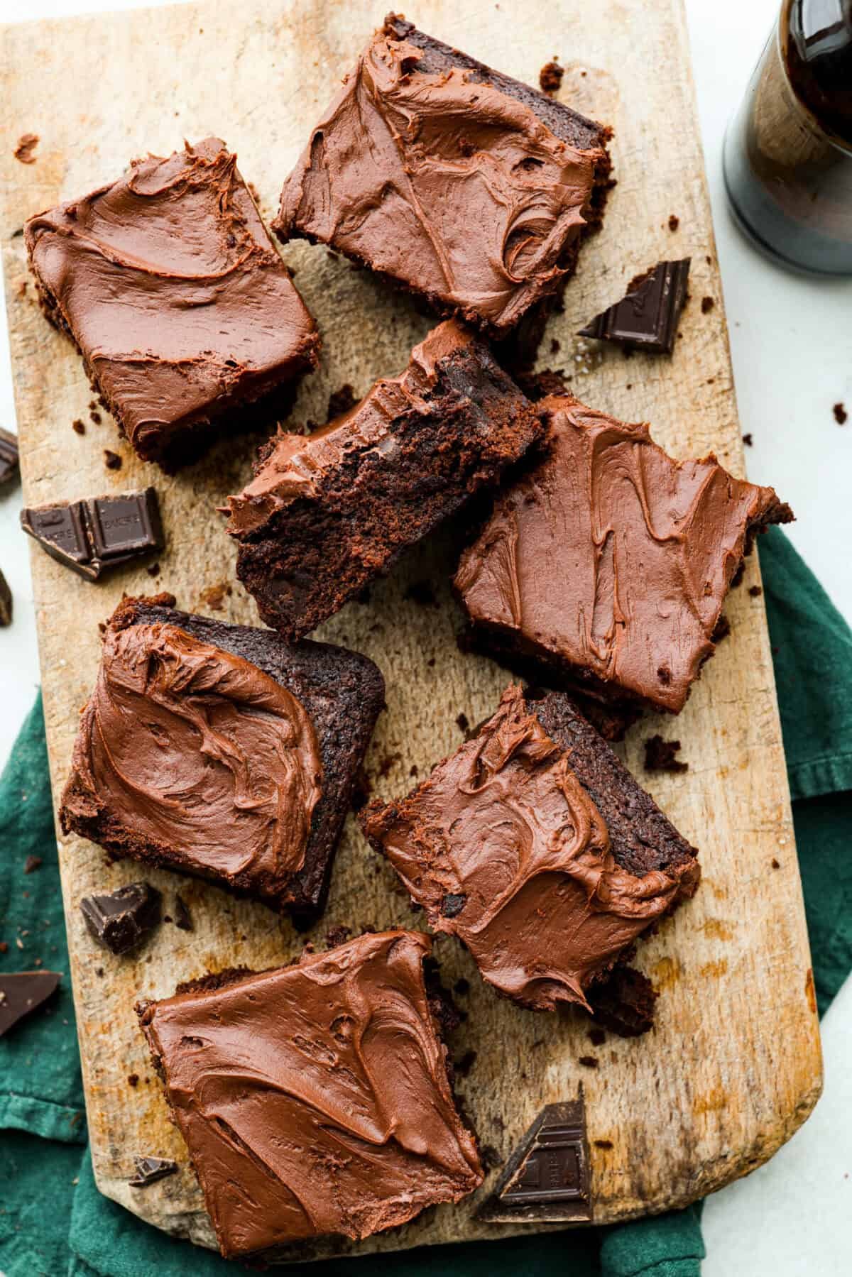 Rich, fudgy, and packed with deep chocolate flavor, Guinness Brownies are a must-try for any dessert lover! The stout beer enhances the cocoa, adding a subtle, malty depth of flavor that makes these brownies rich and irresistibly delicious. Overhead shot of servings of Guinness brownies on a wooden serving board.