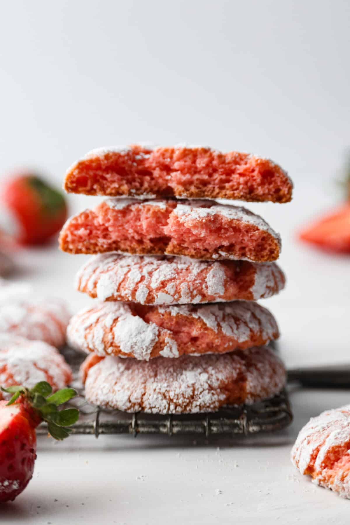 Strawberry Crinkle Cookies are the perfect blend of soft and chewy with a sweet, powdered sugar coating. Their vibrant color and classic strawberry cake flavor make them perfect for any occasion. Side shot of stacked strawberry crinkle cookies.
