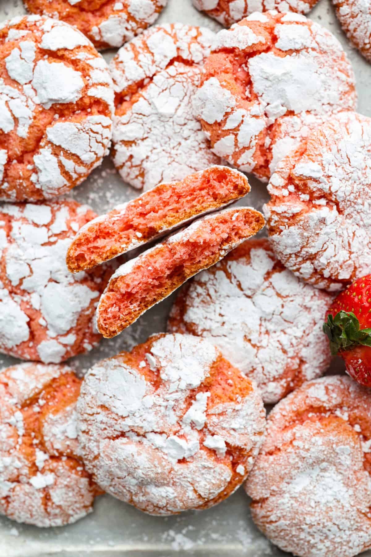 Strawberry Crinkle Cookies are the perfect blend of soft and chewy with a sweet, powdered sugar coating. Their vibrant color and classic strawberry cake flavor make them perfect for any occasion. Close up shot of strawberry crinkle cookies.