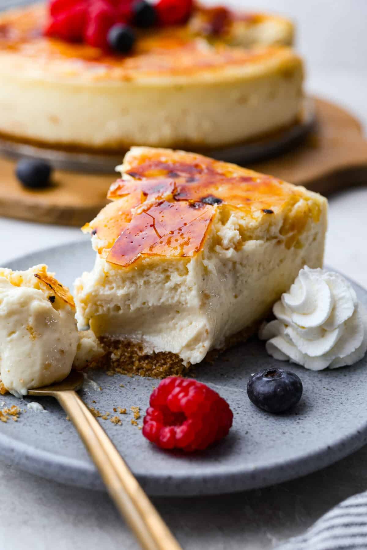 Creme Brulee Cheesecake is the perfect merging of two beloved desserts! It has the rich, creamy texture of cheesecake with the caramelized sugar topping of classic crème brûlée. This irresistible treat is the best of both worlds! Close up shot of a slice of plated creme brûlée cheesecake.