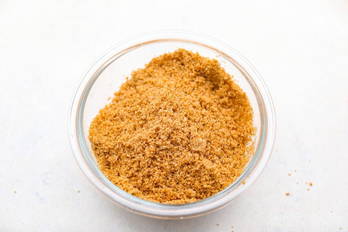 Creme Brulee Cheesecake is the perfect merging of two beloved desserts! It has the rich, creamy texture of cheesecake with the caramelized sugar topping of classic crème brûlée. This irresistible treat is the best of both worlds! Graham cracker crumbs in a small bowl.