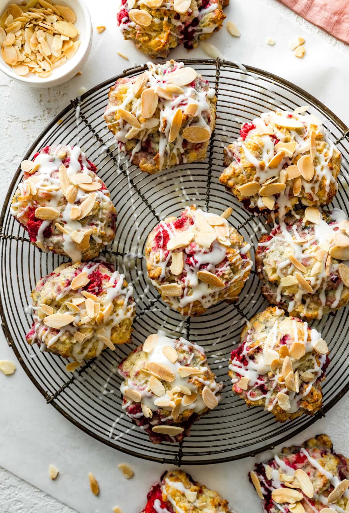 raspberry almond biscuits with almond glaze on cooling rack.