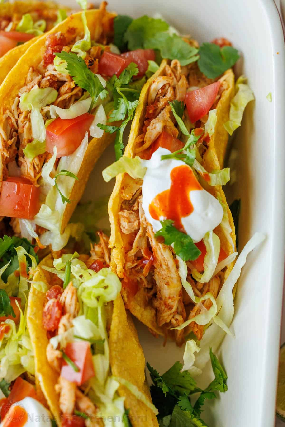 Baked Chicken Tacos are a fast and delicious 30-min meal with shredded chicken over cheesy, crisp tortillas - just add your favorite toppings! Chicken taco recipe topped with sour cream lettuce and hot sauce
