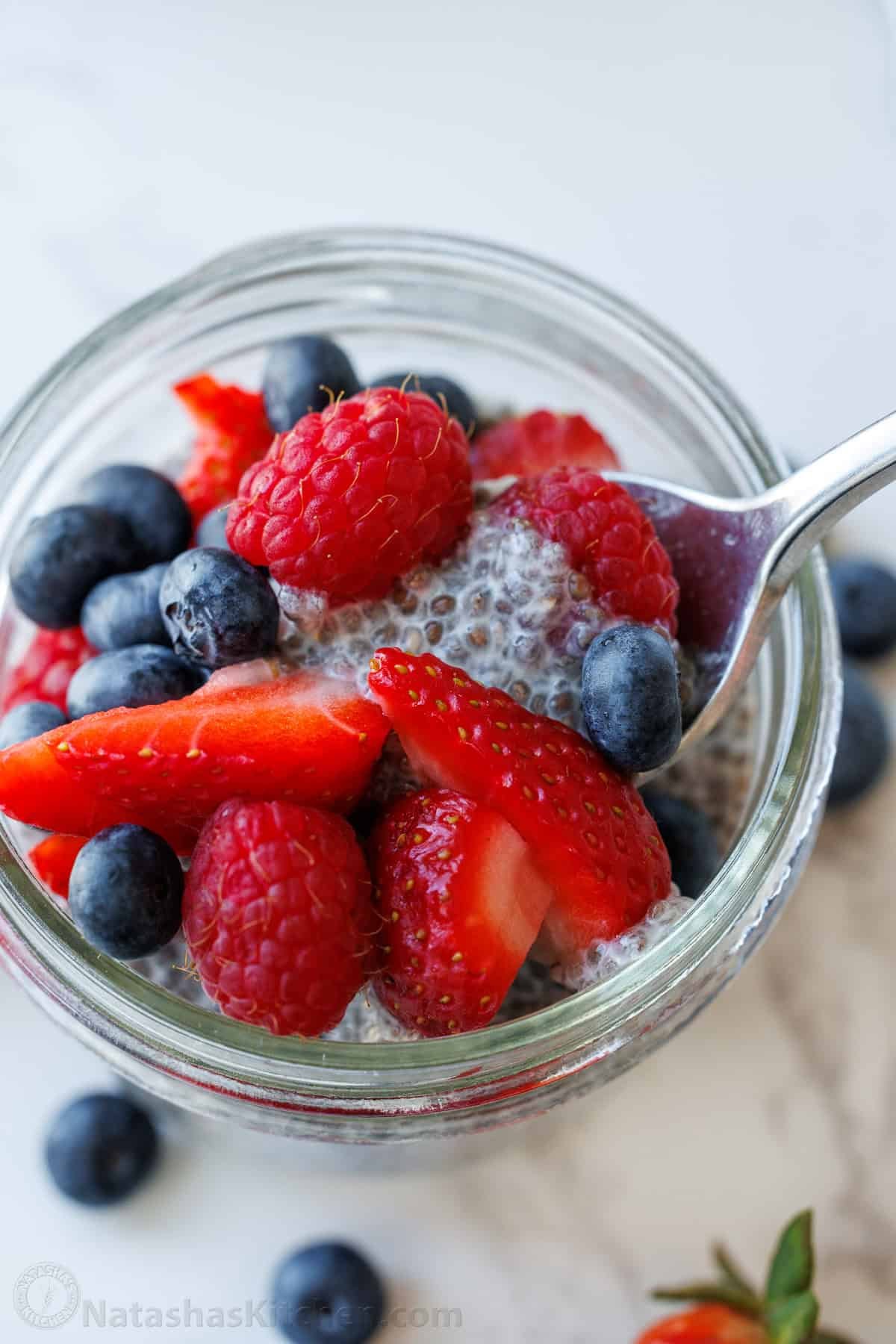 Chia Seed Pudding uses only 3 ingredients to make a delicious and filling breakfast you can prep ahead. Add toppings for the perfect bite. a spoon scopping chia seed pudding out of a mason jar with berries on top