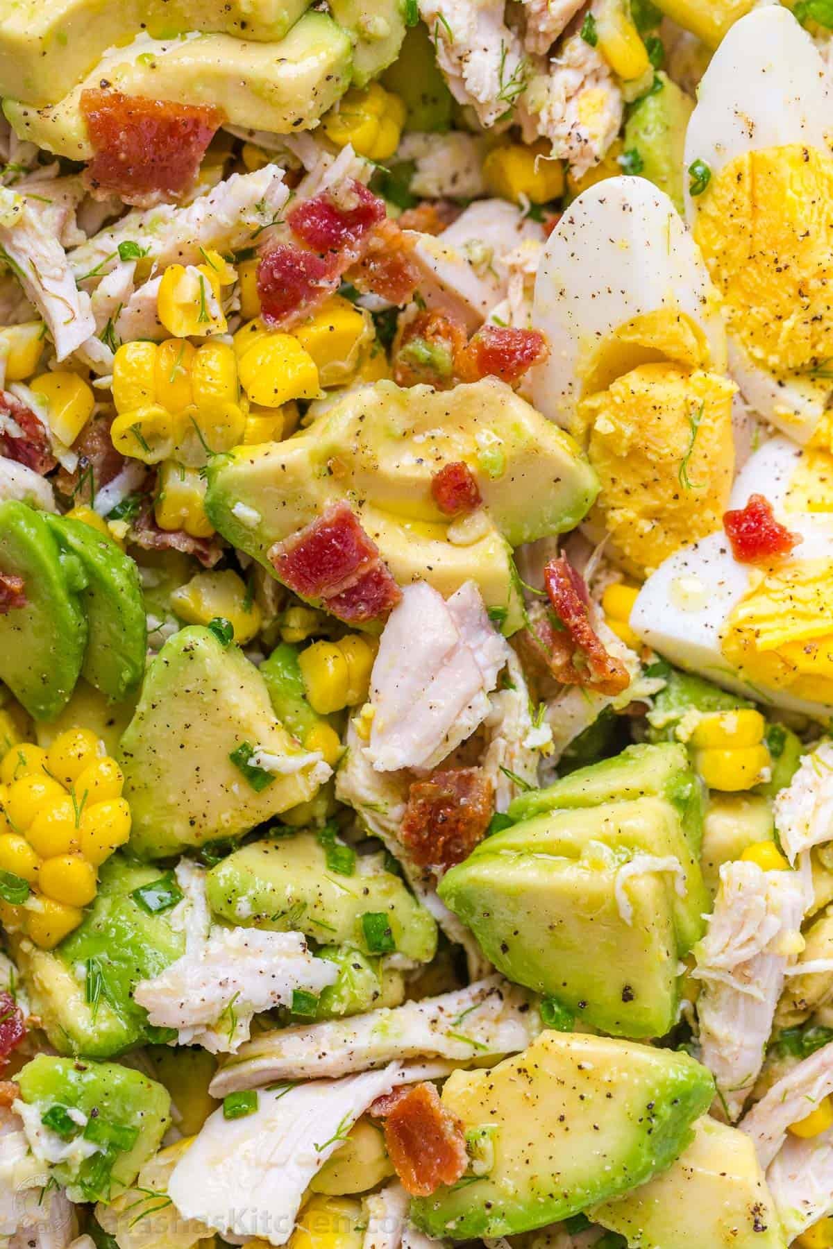 chicken avocado salad mixed with hardboiled eggs, corn and bacon