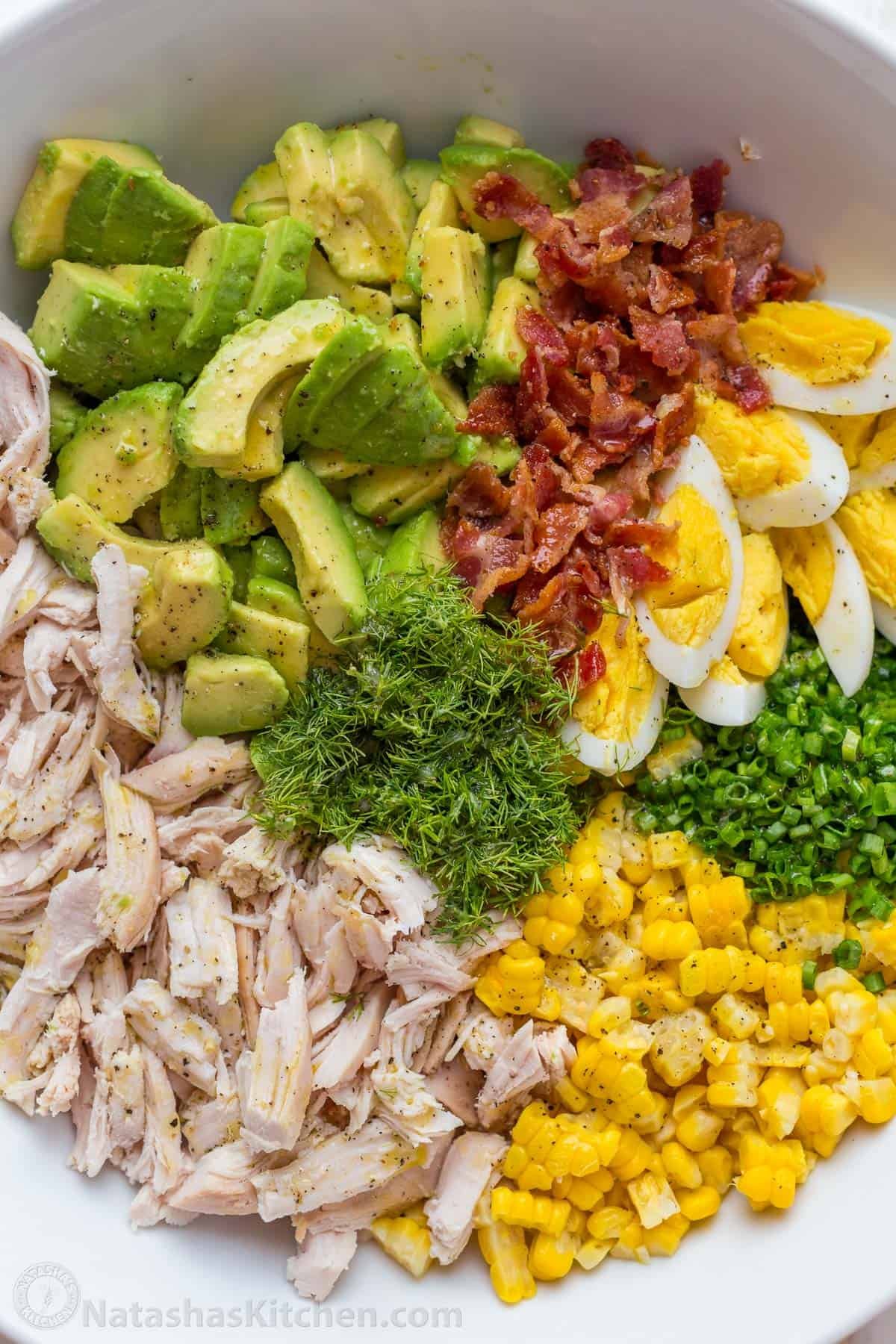 Delicious fresh ingredients in a white bowl for lunch main dish including bacon, eggs, corn, protein, healthy fats and spices