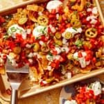 Frito pie on a baking sheet being served with a spatula.