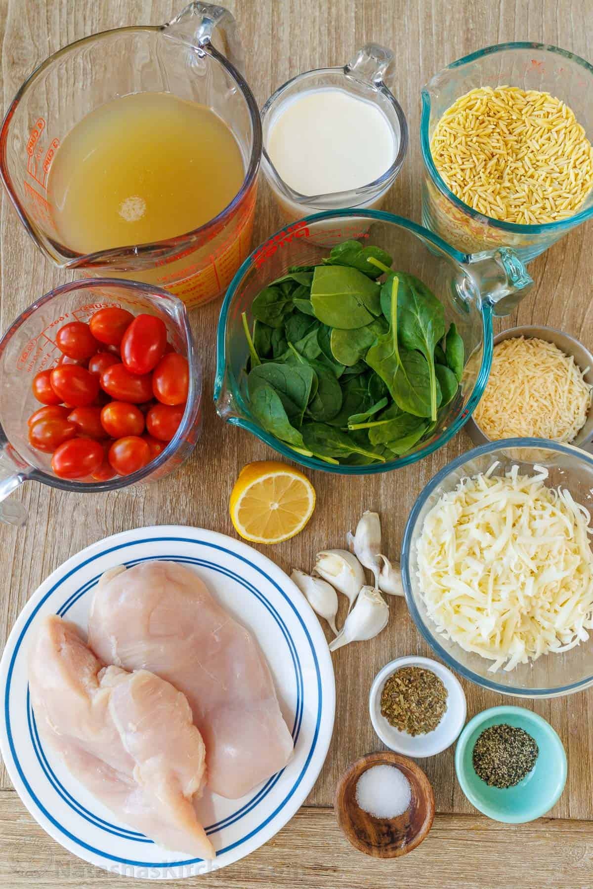 This Chicken Orzo Bake is an easy casserole that's creamy and cheesy. Mix it right in the dish, top it with cheese, and bake! Easy meal prep! Ingredients for orzo chicken bake including chicken stock, heavy whipping cream, orzo, tomatoes, spinach, lemon, garlic, cheese, salt, pepper, oregano, and chicken breasts