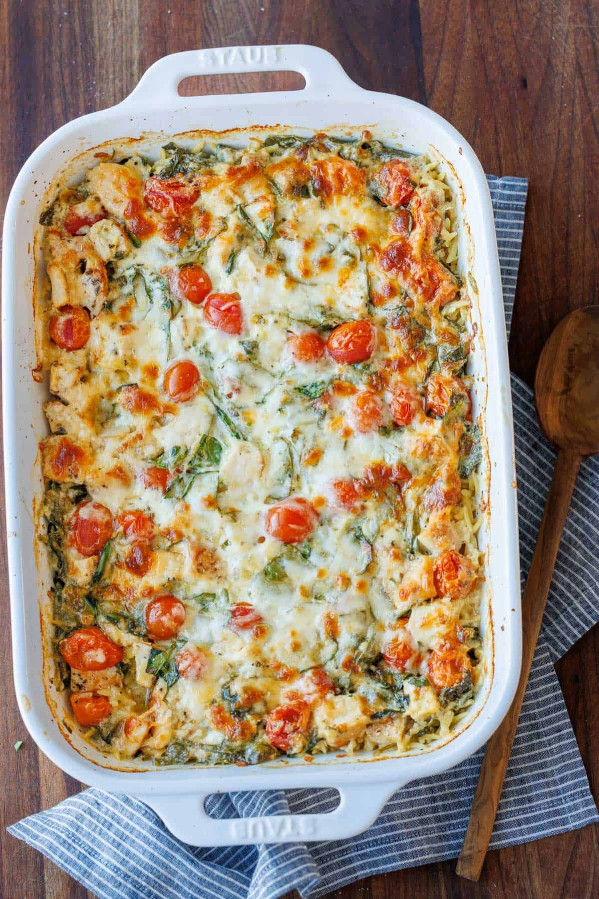 This Chicken Orzo Bake is an easy casserole that's creamy and cheesy. Mix it right in the dish, top it with cheese, and bake! Easy meal prep! Chicken Orzo Bake in a casserole dish with tomatoes and spinach